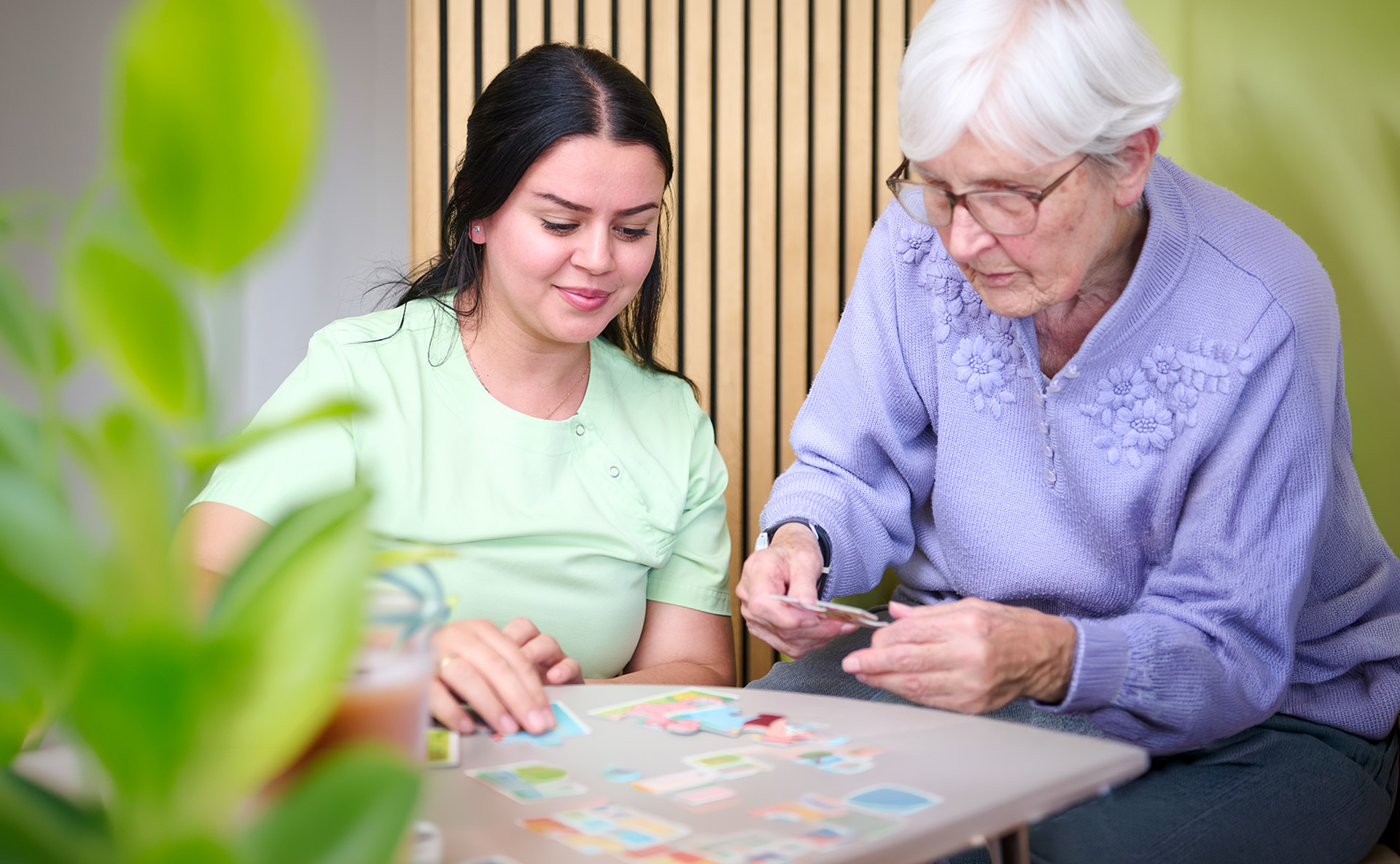 Eine Bewohnerin und eine Pflegerin puzzeln gemeinsam