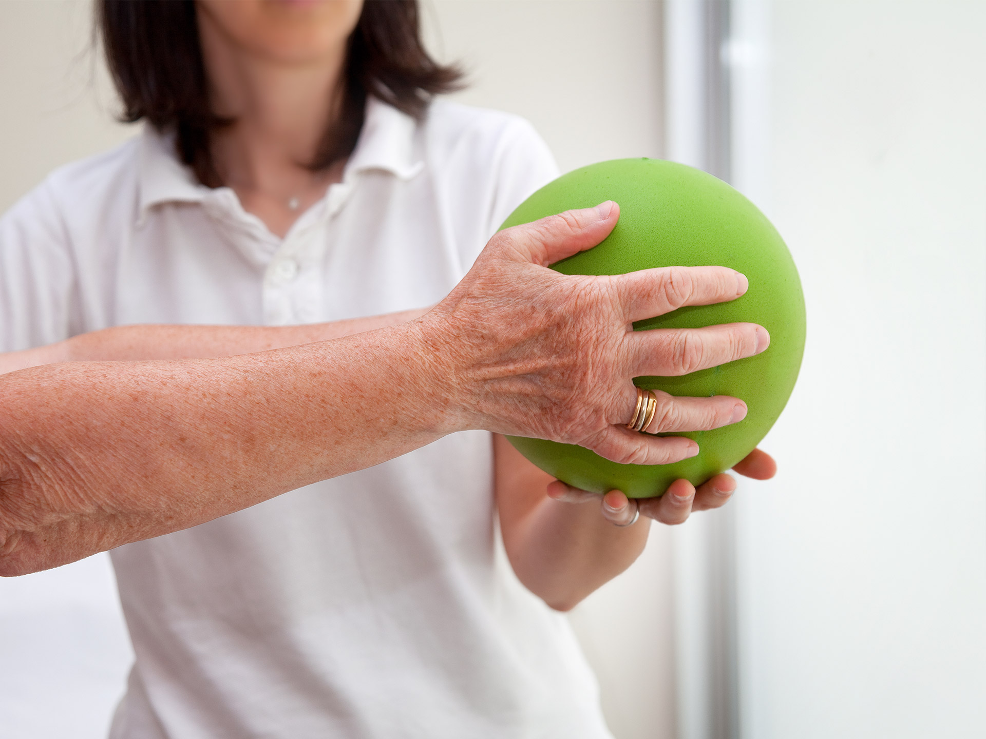 Physiotherapie im Landhaus Neuenegg Eine Physiotherapeutin macht eine Übung mit einem Ball mit einem Bewohner